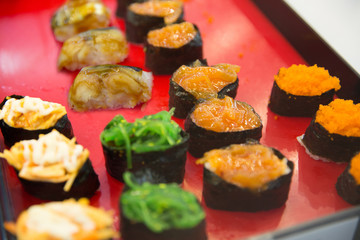 Salmon spicy sushi put on red wood, in focus selective.