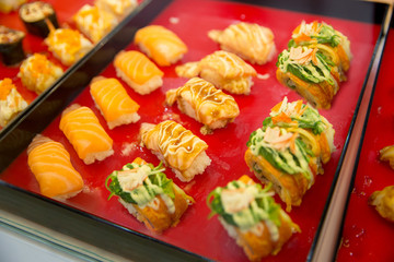 Salmon spicy sushi put on red wood, in focus selective.