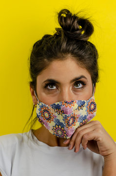 chica joven cabello negro usando mascarilla floreada con fondo amarilo