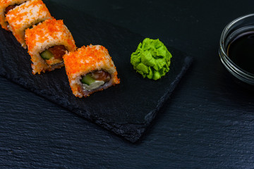 Sushi roll philadelphia with salmon, rice, cheese, cucumber, avocado and caviar on a slate board. Japanese food