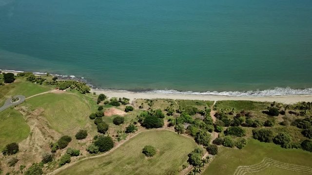aerial view of green areas forest near a white sand beach and blue ocean. Fly Over shot. par2