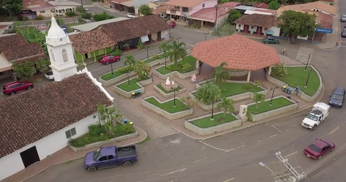 Aerial view of dancing women in folklore pollera in a small park and old white church . aerial pan shot. part2