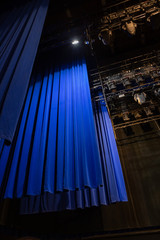 The lights of the stage overhead. Part of the backstage of the Philharmonic concert hall with lighting equipment and a blue curtain. Ceiling lighting equipment.