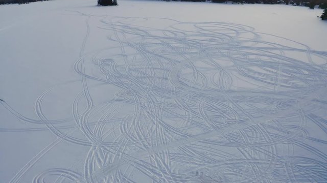 Tracks in the snow on a frozen lake in Ontario Canada.  Lake of The Woods.  Aerial dolly left