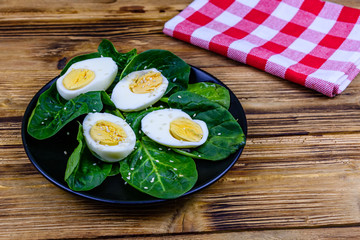 Spinach leaves and halved boiled eggs on a black plate