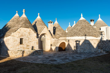 Group of Trulli, traditional old houses and old stone wall in Puglia, Italy