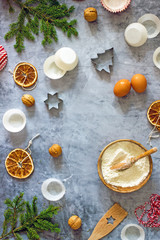 Fototapeta na wymiar Culinary Christmas food background. Baking ingredients, flour, eggs, cookie cutters, fir branches, dried oranges, nuts, paper muffin molds on a dark table. Top view, copy space, flat lay