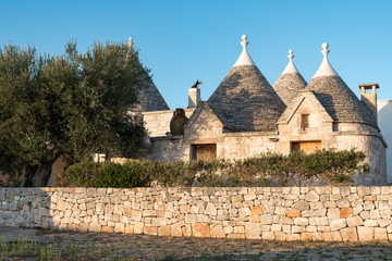 Group of Trulli, traditional old houses and old stone wall in Puglia, Italy