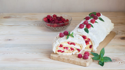 Meringue roulade with cream and raspberries, horizontal orientation, selective focus, copyspace
