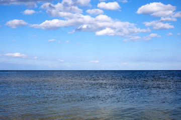 calm sea waters against a blue sky with clouds