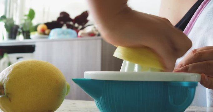 Squeezing the juice out of a lemon.  Making lemon juice squeezed by caucasian hand woman, inside a home kitchen. Healthy vitamins C