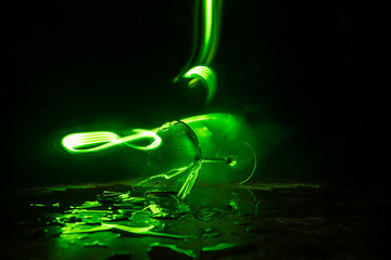Broken glasses on wooden table at dark toned background with fog. Selective focus