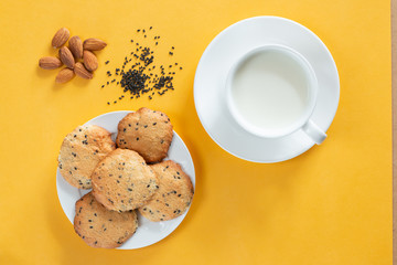Homemade cookie with almond and black sesame, cap of milk on yellow background