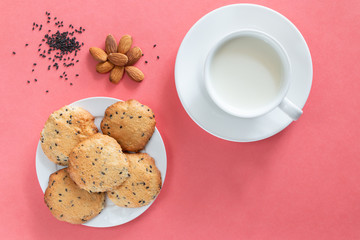 Homemade cookie with almond and black sesame, cap of milk on magenta background