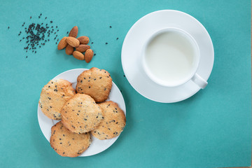 Homemade cookie with almond and black sesame, cap of milk on cyan background