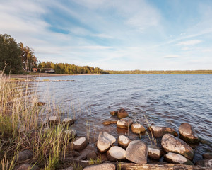 Huge stones on the river bank. Vuoksa river near Imatra in the Leningrad region, Russia. Coastline with birch, pine tree forest reflected in Vuoksa water, near Finland.