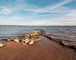 Huge stones on the river bank. Vuoksa river near Imatra in the Leningrad region, Russia. Coastline with birch, pine tree forest reflected in Vuoksa water, near Finland.