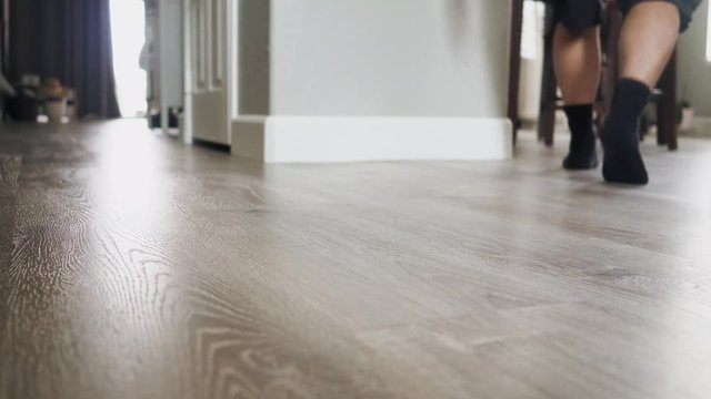 Man walking to dining table to read a birthday card and drops it on the floor.  Wide shot