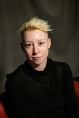 Portrait of a young woman with short blonde hair at ease.