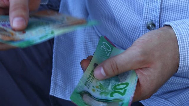 A Man In A Business Shirt Counting New Zealand Money. Lots Of Different  Dollars