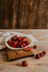 scattered juicy fresh red strawberries on the table with vintage plank. mint leaf. drops and splashes of spilled milk. vegetable cutting board. High quality photo