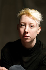 Portrait of a young woman with short blonde hair wondering.