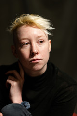 Portrait of a young woman with short blonde hair thinking.