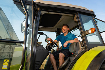 Naklejka premium Bäuerliche Landwirtschaft, junger Landwirt auf einem Traktor.