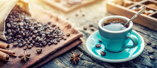 A blue cup of aromatic black coffee and coffee beans on the table. Morning Coffee Espresso for...