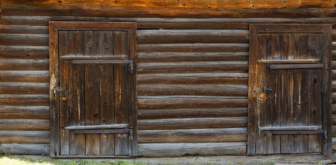 Two wooden doors in an old log building. Front view. Texture background.
