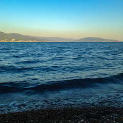 The waves of the sea come ashore in the bay. Square aspect ratio. Shallow focus.