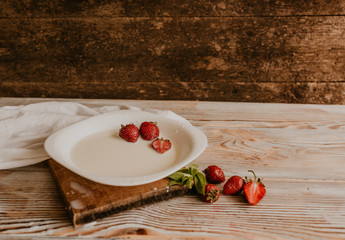 scattered juicy fresh red strawberries on the table with vintage plank. mint leaf. drops and splashes of spilled milk. vegetable cutting board. High quality photo