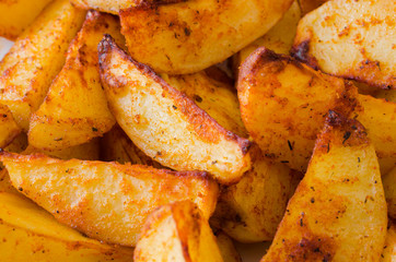 Golden spicy potato wedges fried or oven baked closeup.