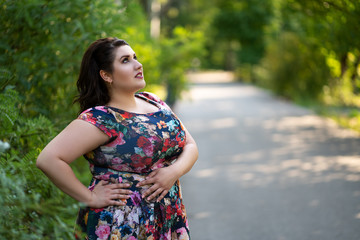 Fototapeta premium Plus size fashion model in floral dress outdoors, beautiful fat woman with beauty makeup and hairstyle