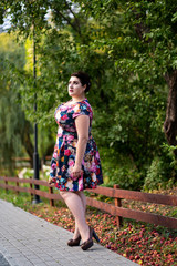 Naklejka premium Plus size fashion model in floral dress outdoors, beautiful fat woman with big breasts in nature