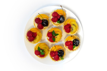 top down view of a plate of fruit tartlets on a white surface