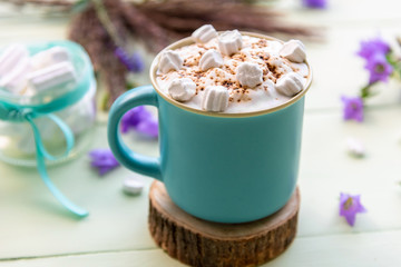 Hot coffee drink with marshmallows and foam in a light blue Cup.
