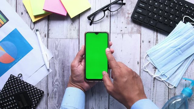 top view of man hand using smart phone on office desk 