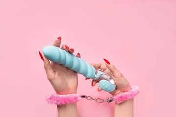 Dildo in hand on a pink background, sex toy