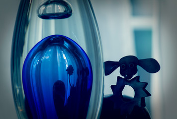 Metal poodle dog and its reflection in a blue glass flask, abstract design