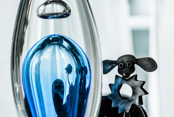 Metal poodle dog and its reflection in a blue glass flask, abstract design © maaramore©	