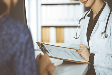 Doctor and patient discussing current health examination while sitting in clinic. Perfect medical...