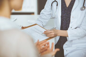 Doctor and patient discussing current health examination while sitting in clinic. Perfect medical...