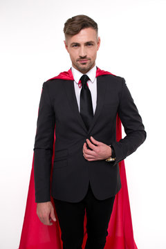 Just call me superhero. Handsome young man in red cape looking at camera while standing against white background

