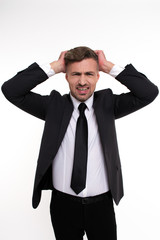 Real problems. Handsome young man keeping head in hands and looking at camera while standing against white background

