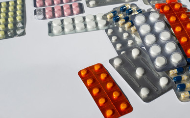  Blisters with pills lie in a pile on a white background. Copy space for text.