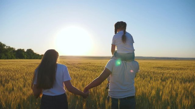 Happy family, people. Family lifestyle. Beautiful sunset on a wheat field. A happy child on the shoulders of a caring father. A walk in the Park.