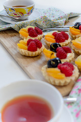 fruit tartlets being served with cups of tea
