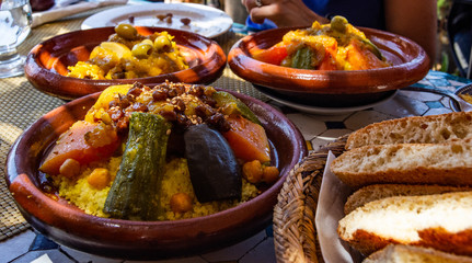 Couscous (Arabic: كُسْكُس‎ ) is a Maghrebi dish of small (about 3mm diameter) steamed balls of crushed durum wheat semolina, usually served with a stew spooned,vegetables at family gatherings.