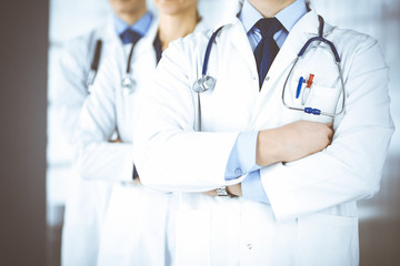 Group of modern doctors standing as a team with crossed arms and stethoscopes in hospital office....